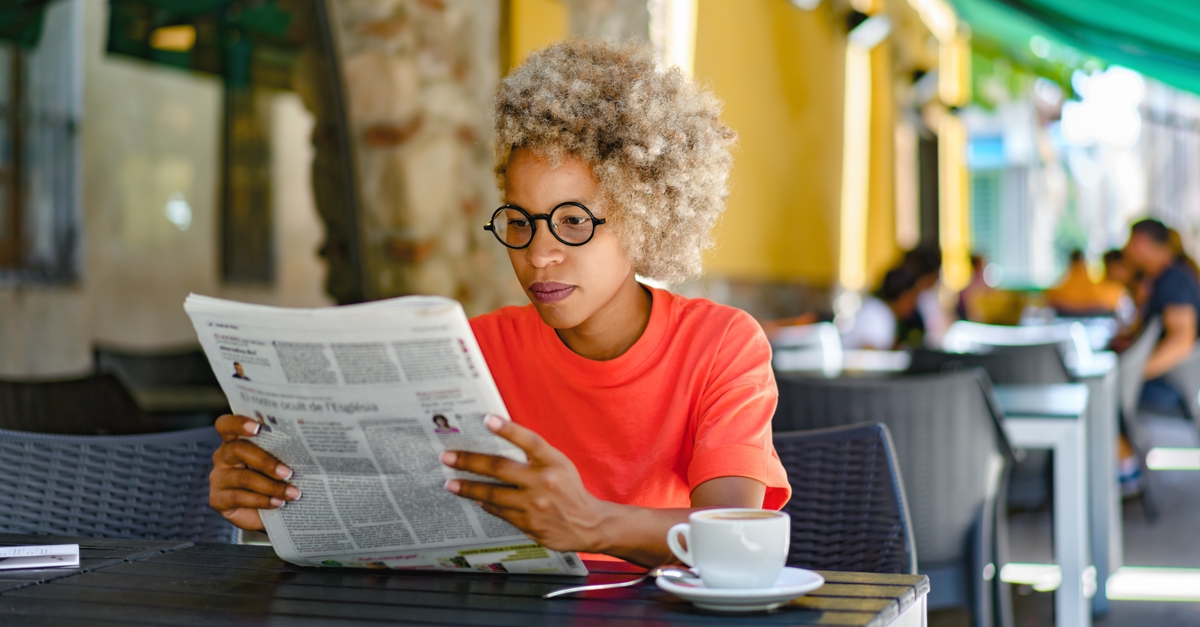Woman reading newspaper at a cafe.